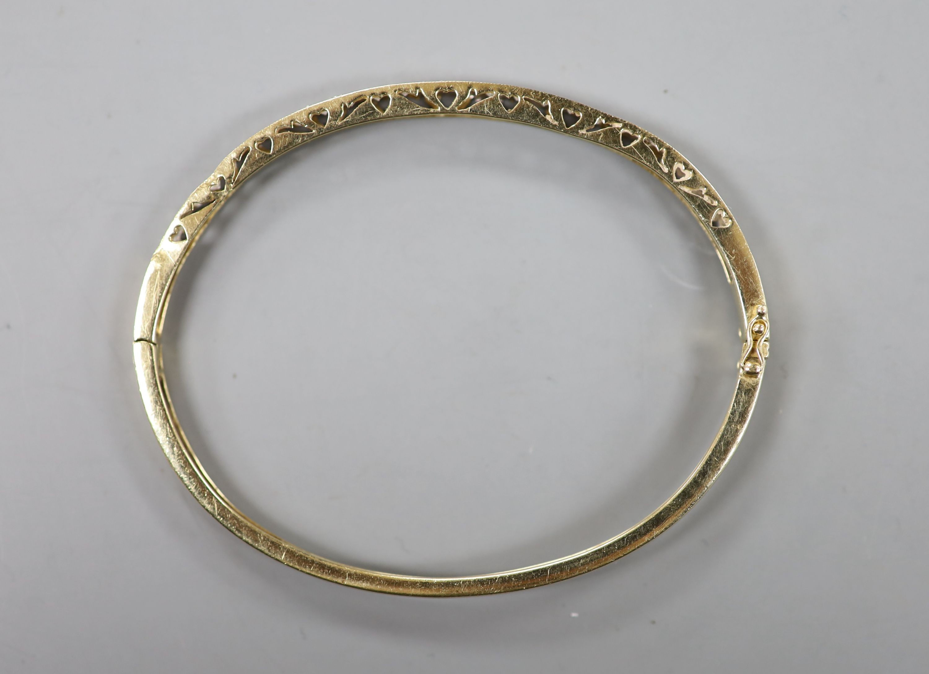 A modern 585 yellow metal and diamond chip set hinged bangle, interior diameter 62mm